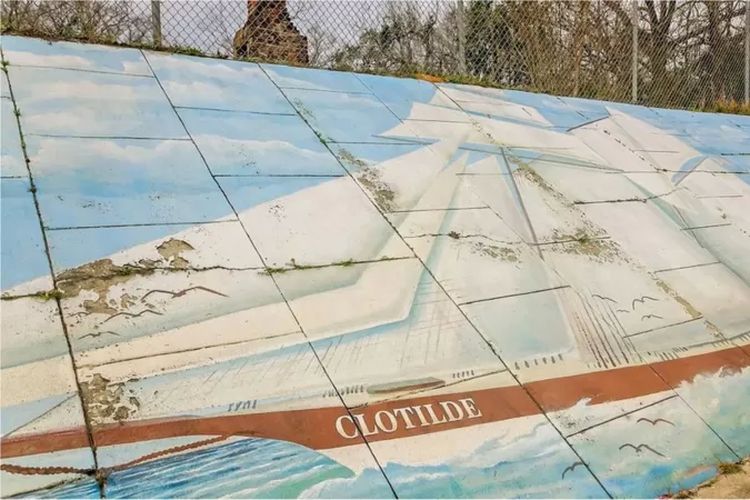 Sebuah mural kapal Clotilda terpasang di pinggir jalan yang memisahkan dua sisi permukiman Africatown.