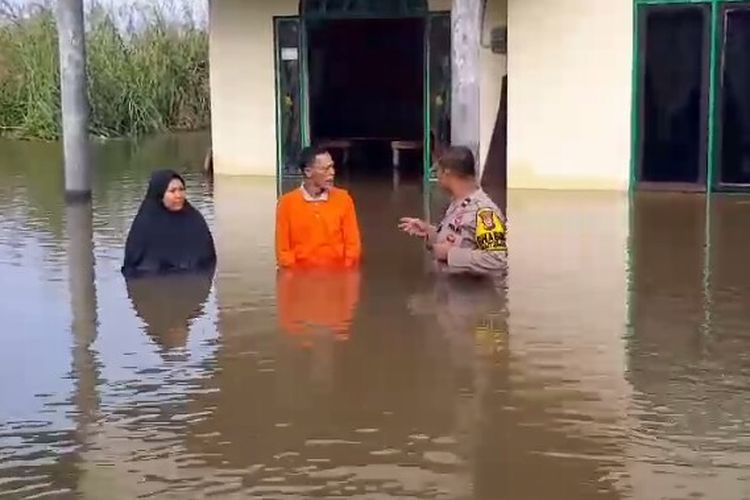 Petugas kepolisian memantau kondisi warga yang dilanda banjir di Desa Teratak Buluh, Kecamatan Siak Hulu, Kabupaten Kampar, Riau, Selasa (2/1/2024).