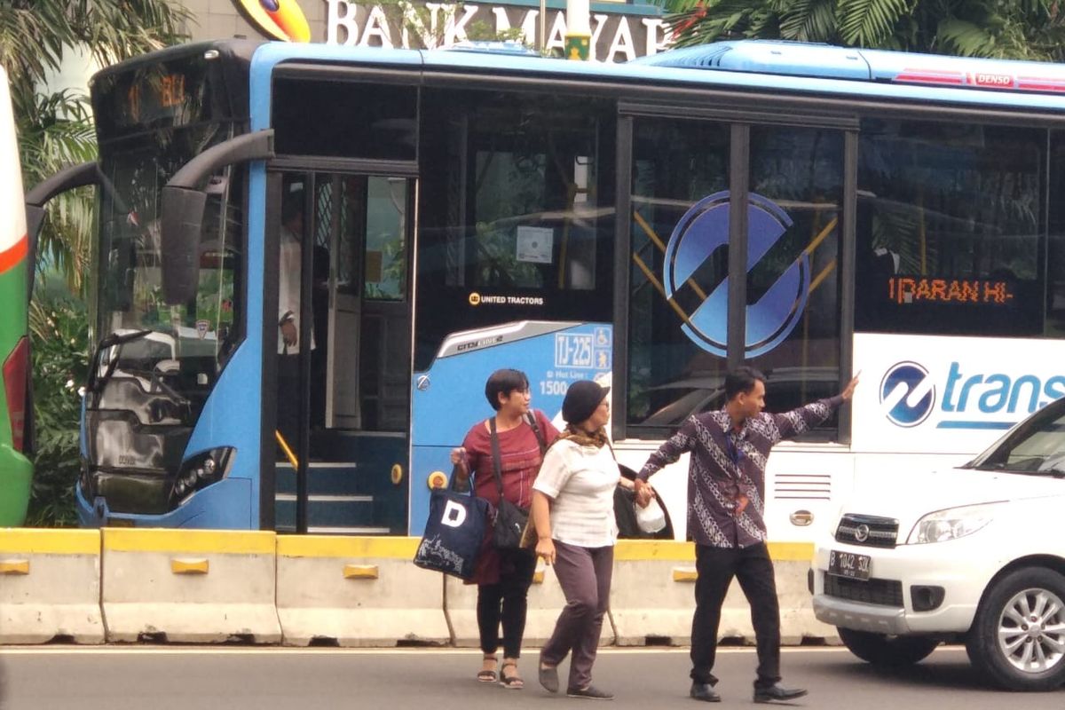 Petugas Transjakarta membantu penumpang menyeberang jalan. Penumpang turun di tengah jalan karena bus transjakarta terjebak macet imbas adanya demo di Gedung Bawaslu RI, Jumat (10/5/2019).