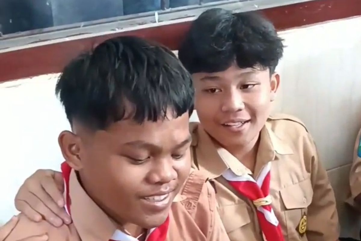Enggar saat dirangkul temannya dalam momentum pemberian sepatu. Rekan-rekan Enggar di SMK PGRI 1 Kota Kediri, Jawa Timur, patungan dari uang jajann untuk membelikannya sepatu lalu video itu viral.