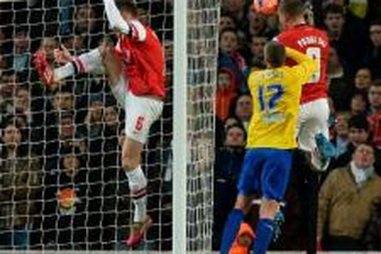 Striker Arsenal, Lukas Podolski (kanan), menyundul bola yang berbuah gol untuk timnya saat berhadapan dengan Coventry City pada putaran keempat Piala FA di Stadion Emirates, London, Jumat (24/1/2014).