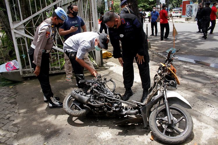 Members of a police bomb squad inspect the wreckage of a motorbike used to carry out Sunday's suicide bomb attack at the Sacred Heart of Jesus Cathedral in Makassar, South Sulawesi, Indonesia, on Monday, March 29.