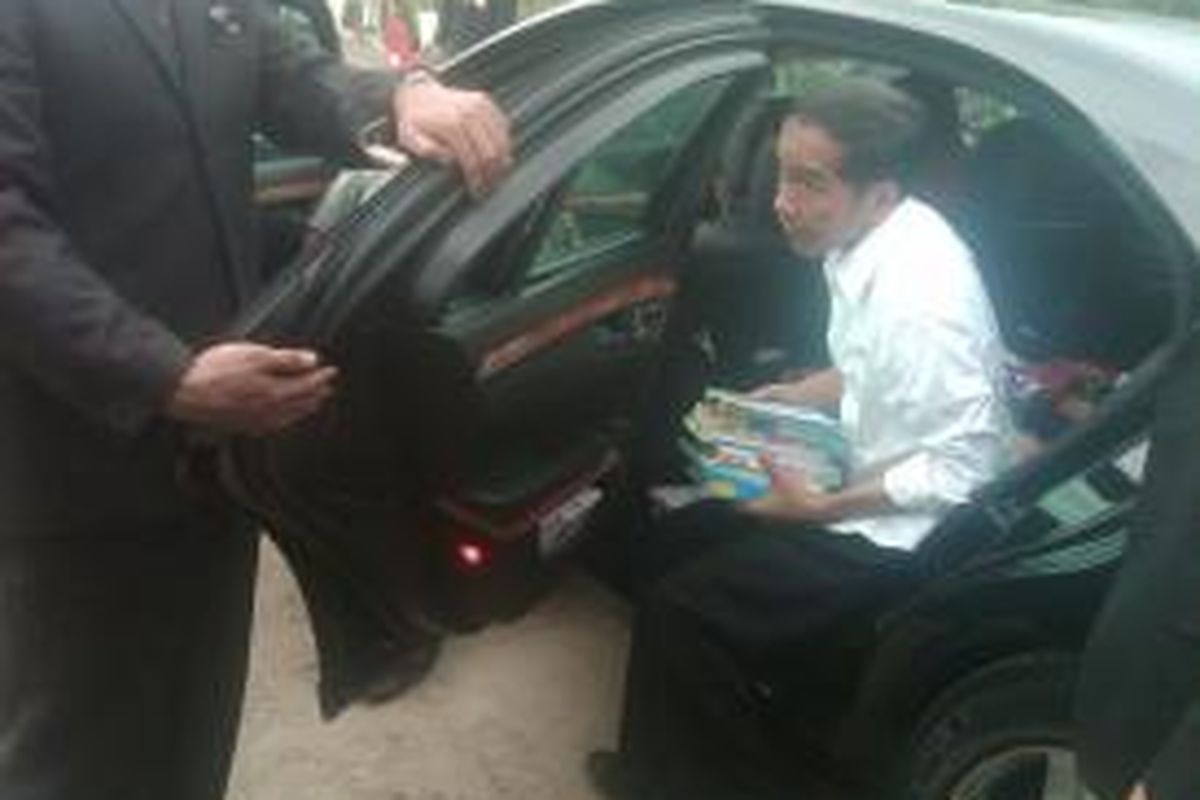 Presiden Joko Widodo membawa buku untuk dibagi-bagikan kepada anak-anak saat kunjungannya ke Ngawi, Sabtu (31/1/2015)