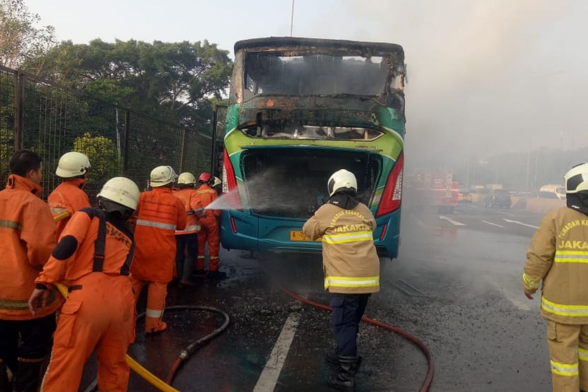 Petugas pemadam kebakaran memadamkan bus penumpang yang terbakar pada Kamis (13/6/2019) pagi di ruas Tol Lingkar Luar Barat arah Cengkareng.