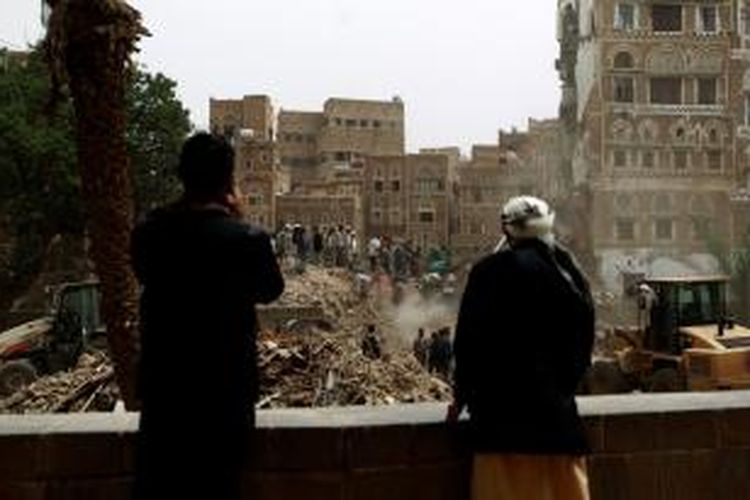 Warga kota tua Sana'a, Yaman menyaksikan reruntuhan bangunan tua yang hancur dihantam serangan udara Arab Saudi, Jumat (12/6/2015). Padahal kawasan ini dikenal sebagai permata kebudayaan Islam dan masuk dalam daftar warisan dunia UNESCO.