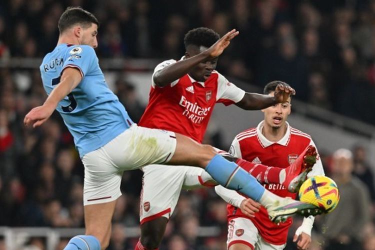 Bek Man City, Ruben Dias (kiri), berduel dengan pemain Arsenal, Bukayo Saka (kanan), dalam laga lanjutan Liga Inggris yang mempertemukan Arsenal vs Man City di Stadion Emirates pada 15 Februari 2023. Terkini, laga Man City vs Arsenal masuk dalam rangkaian pekan ke-33 Liga Inggris 2022-2023. Artikel ini berisi jadwal Liga Inggris. (Foto oleh Glyn KIRK / AFP).