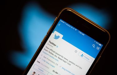 Ilustrasi Aplikasi Twitter di ponsel di depan logo Twitter