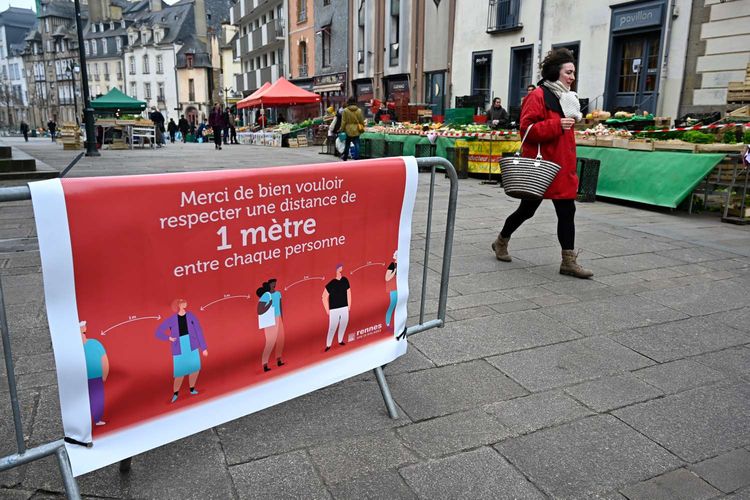 Orang melintasi banner bertuliskan terima kasih untuk menjaga jarak 1 meter dengan tiap orang saat warga mengantre belanja di pasar Marche des Lices, di Pusat Kota Rennes, Barat Perancis, 21 Maret 2020. Menjaga jarak aman antar orang menjadi salah satu cara yang disarankan untuk mencegah penyebaran virus corona.