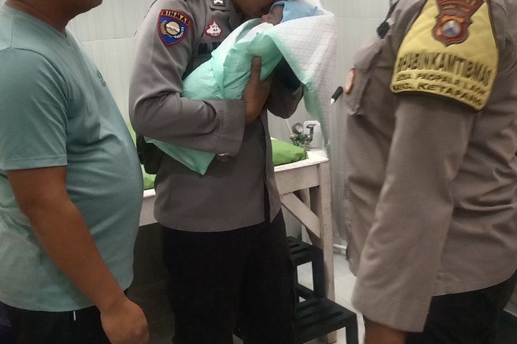 Bhabinkamtibmas Desa Ketapang Barat, Bripka Moh. Jufri mengadzani bayi laki-laki yang ditemukan di tepi sawah, Kamis (26/6/2025). 