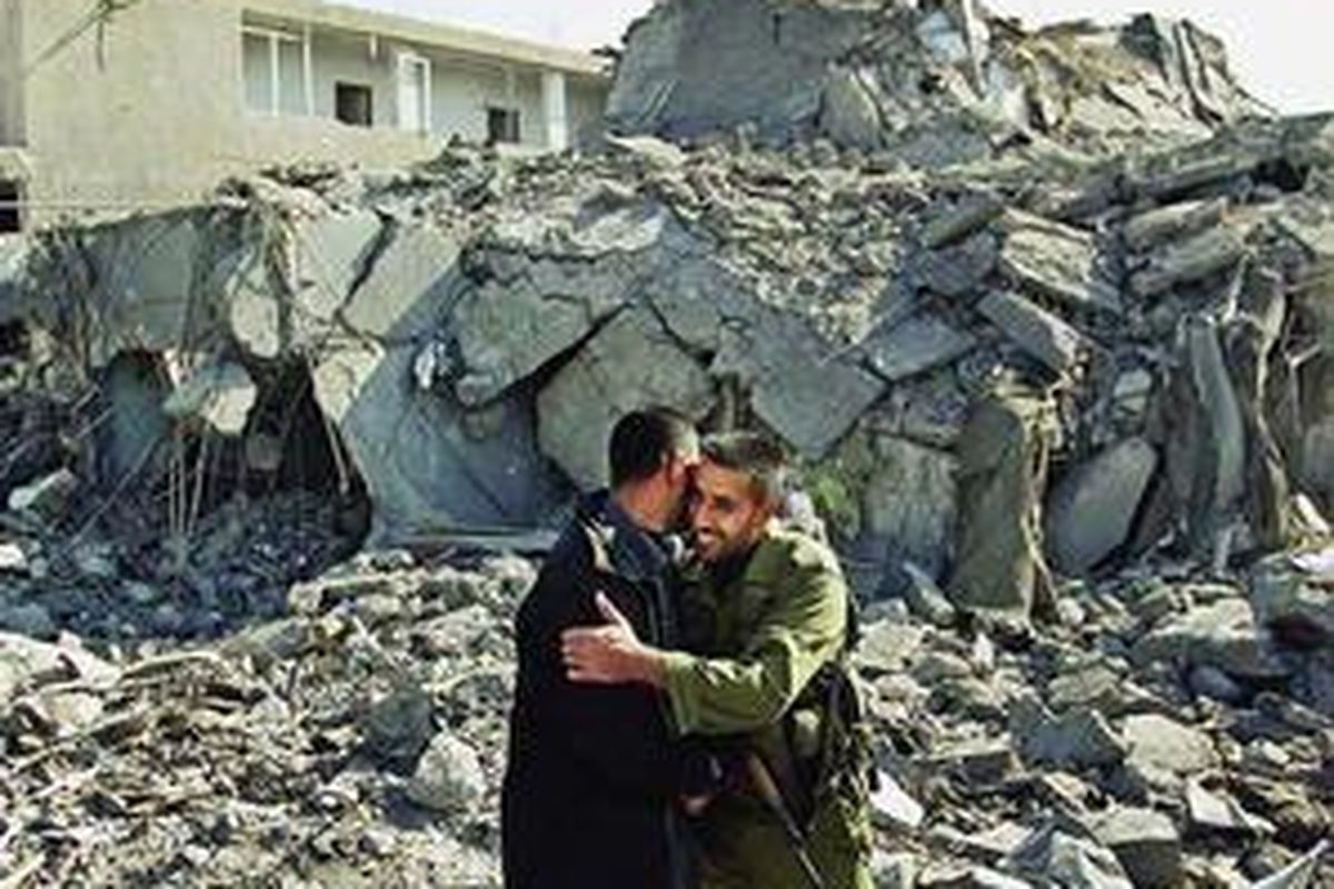 Pejabat polisi Hamas, Palestina, berpelukan di tengah puing-puing markas keamanan dan penjara pusat di Gaza City, Jalur Gaza, Rabu (21/1). Markas keamanan ini hancur akibat serangan udara Israel, akhir Desember lalu. Jalur Gaza relatif tenang menyusul gencatan senjata.