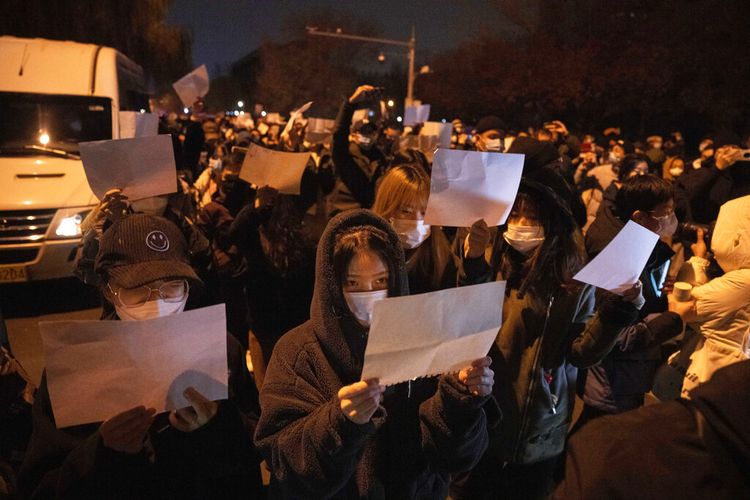 Para demonstran memegang kertas kosong dan meneriakkan slogan-slogan saat mereka menggelar protes di Beijing, Minggu, 27 November 2022.