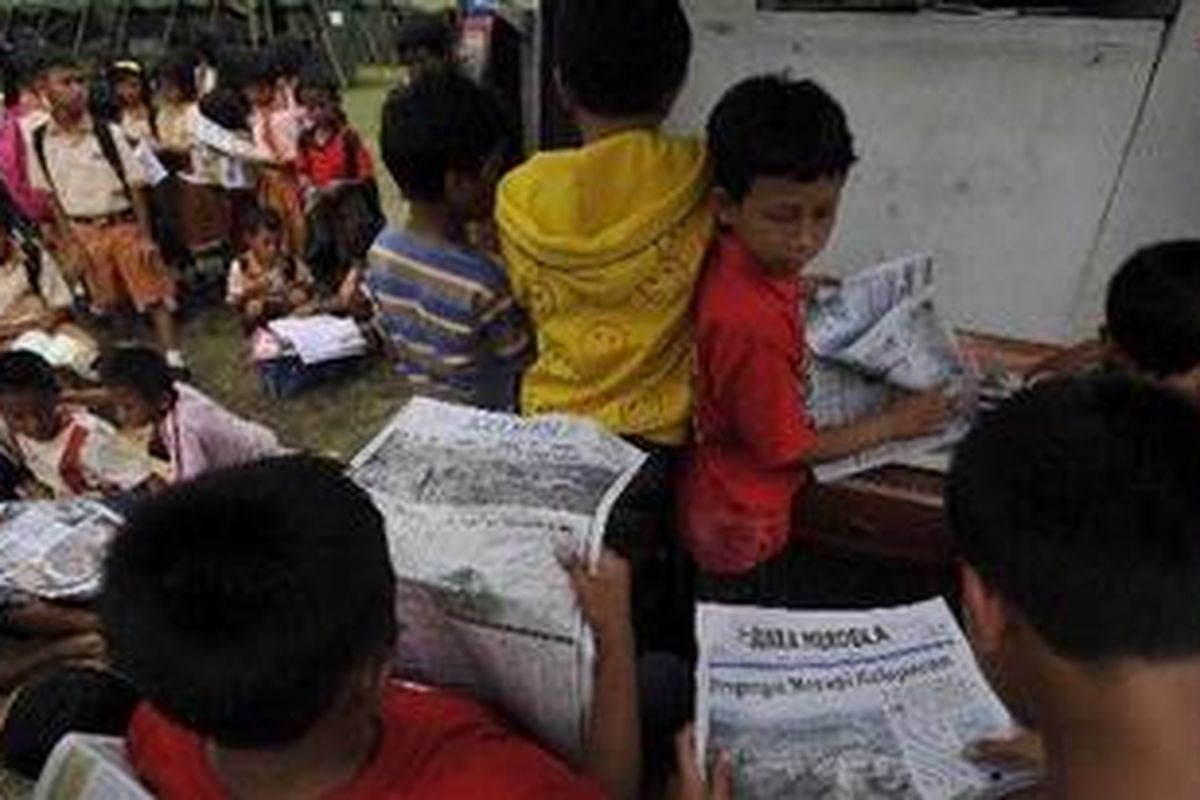 Anak-anak korban letusan Merapi dari Desa Sidorejo, memanfaatkan waktu luang dengan membaca buku dan koran yang ada di mobil perpustakaan keliling yang didatangkan khusus ke tempat pengungsian di Desa Keputran, Kecamatan Kemalang, Kabupaten Klaten, Kamis (28/10/2010). 