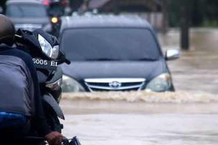 Sejumlah pengguna kendaraan roda empat nekat menerobos ruas jaln tergenang banjir di kawasan  Gampong Baro, Kecamatan Teunom, Kabupaten Aceh Jaya, Kamis (5/1/2017)