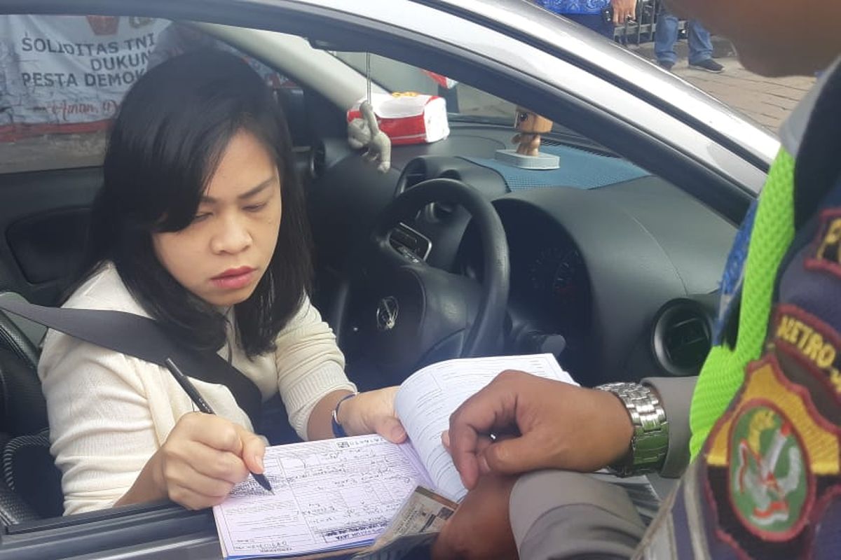 Salah satu pengendara menandatangani surat tilang karena kendaraannya terjaring operasi ganjil genap di Traffic Light Tomang Raya, Jakarta Barat, Senin (9/9/2019).