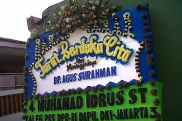 Sebuah karangan buka dipasang di depan kediaman rumah kakak ipar, Agus Surahman (31), Rorotan, Jakarta Utara, Selasa (10/9/2013). Agus adalah korban tewas kecelakaan maut di tol Jagorawi Km 8 200, Minggu (8/9/2013) dini hari.
