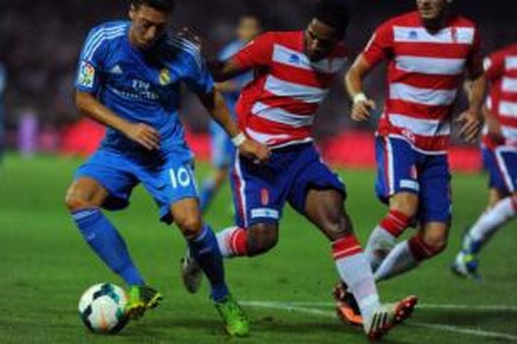 Gelandang Real Madrid, Mesut Oezil (kiri), berakhir saat melawan Granada di Stadion Los Carmenes, Granada, Senin (26/8/2013).