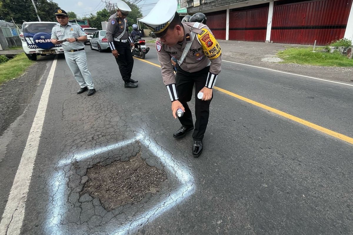 Petugas menandai jalan yang berlubang dengan cat putih dalam pengecekan jalur mudik pantura di Provinsi Bali, Rabu (19/2/2025).