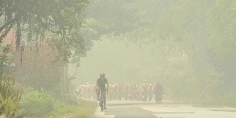Para pebalap menembus pekatnya kabut asap dalam etape ketiga Tour de Singkarak dari Desa Adat Sijunjung menuju Sport Centre Koto Baru, Sumatera Barat, Senin (5/10/2015). Pada etape ini, para pebalap mengayuh sepeda sejauh 184,5 kilometer.
