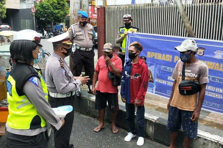 Petugas Direktorat Lalulintas (Ditlantas) Polda Maluku membagikan sembako kepada tukang becak dan tukang ojek di sela-sela operasi Patuh Siwalima di Ambon, Selasa (21/9/2021)