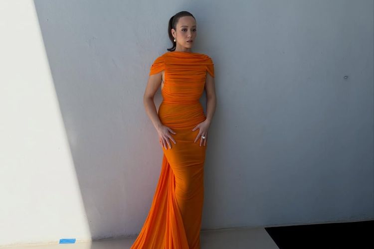 Laufey curi perhatian di Golden Globes 2026. Tampil bold dengan gaun Balenciaga oranye. Cek detailnya.