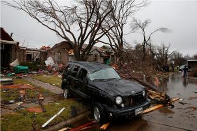 Sebuah mobil teronggok di depan rumah setelah badai tornado menerjang kawasan Rockwall, Texas, Minggu (27/12/2015).