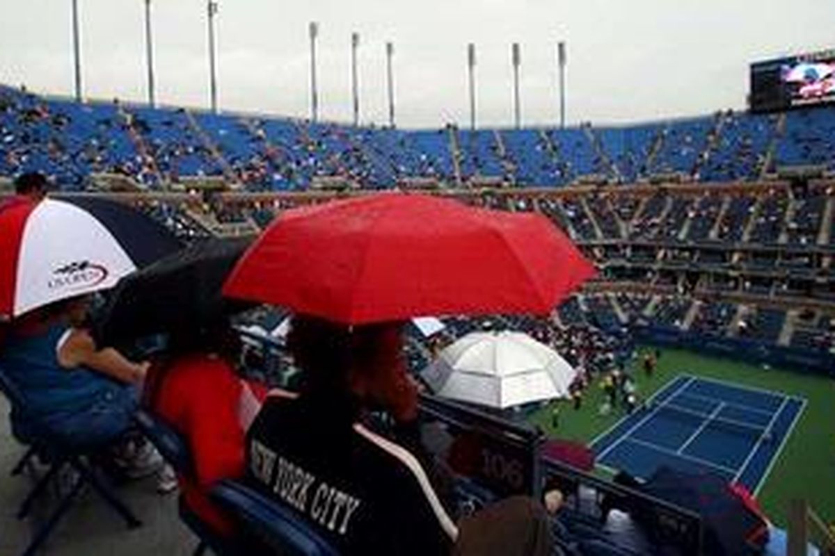 Para penonton laga Maria Sharapova melawan Marion Bartoli harus mengembangkan payung mereka saat hujan mengguyur arena pertandingan.