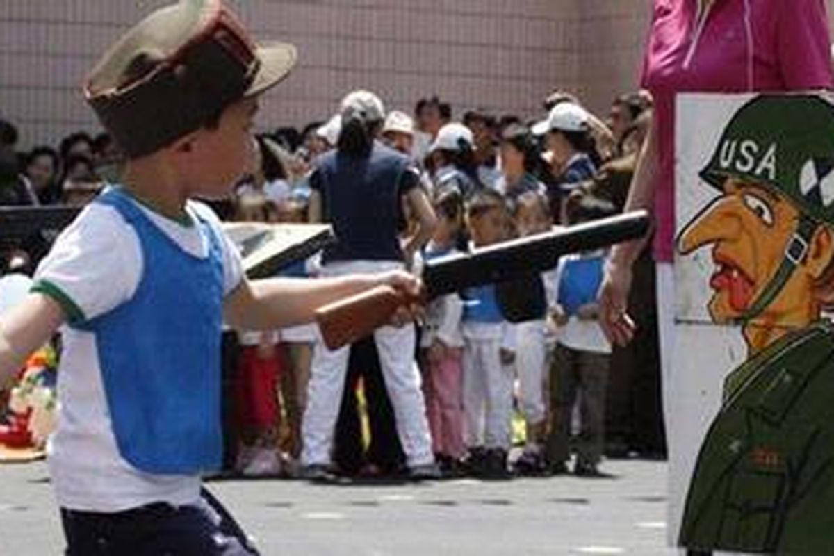 Seorang anak mengacungkan senapan mainannya ke arah gambar "tentara AS" dalam sebuah permainan di sebuah taman kanak-kanak di Pyongyang, Korea Utara, pada perayaan Hari Anak Internasional, 1 Juni 2012.
