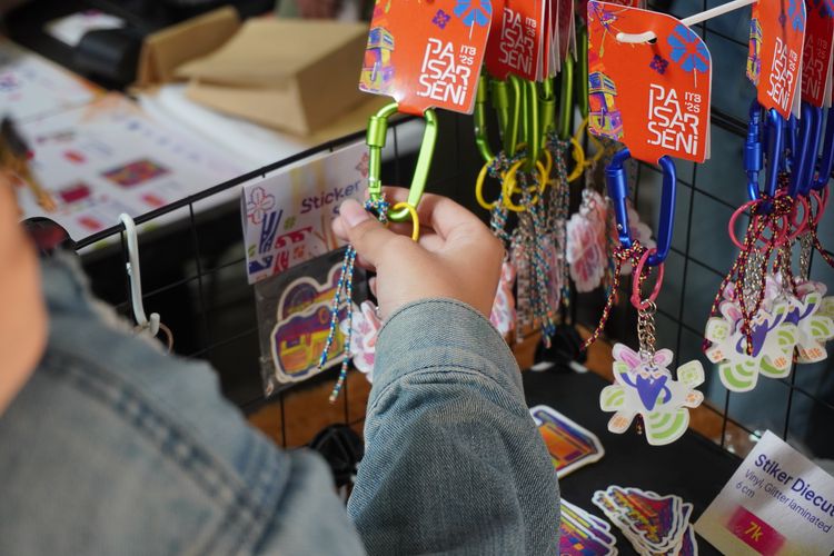 Seorang pengunjung sedang melihat produk kreatif mahasiswa dan alumni ITB dalam Saling Senggol, rangkaian acara menjelang Pasar Seni ITB 2025.  