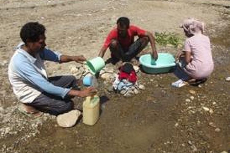 Ketua RT 016  Dusun Halimuti, Kabupaten Belu, Nusa Tenggara Timur, Gabriel Valente (baju merah) bersama dua warga lainnya sementara mengambil air di kali yang sudah tercemar kotoran hewan, yang dipakai untuk keperluan minum, masak dan cuci, Sabtu (7/6/2014)