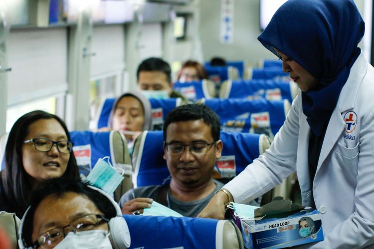 Petugas medis dari PT KAI DAOP 1 Jakarta membagikan masker pada calon penumpang kereta api di Stasiun Gambir, Jakarta, Jumat (31/1/2020). Pembagian masker gratis pada calon penumpang dalam rangka mengantisipasi penyebaran virus corona.