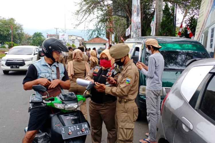 Anggota Satpol PP mencatat identitas warga yang tidak menggunakan masker saat berkendara dalam razia masker, Senin (24/08/2020)