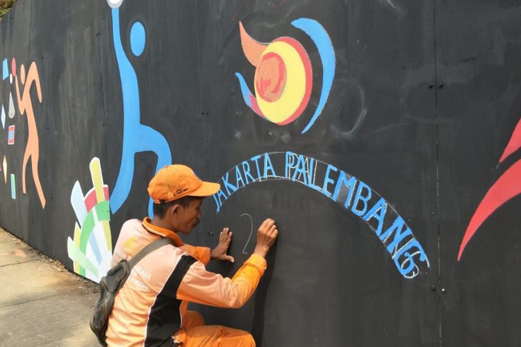 Petugas penanganan prasarana dan sarana umum (PPSU) atau pasukan oranye Kelurahan Pondok Pinang menggambar mural Asian Games 2018 di perempatan Pondok Indah Mall, Jakarta Selatan, Rabu (25/7/2018).