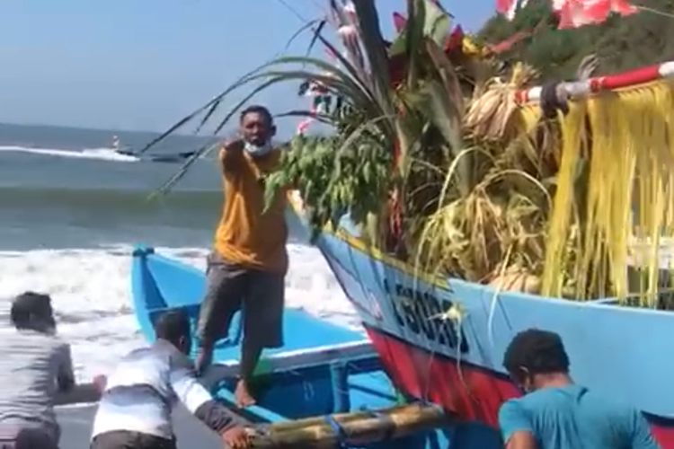 Melarung sesaji berisi kepala sapi, hasil bumi dan laut, saat petik laut di Pantai Lampon, Selasa (10/8/2021).