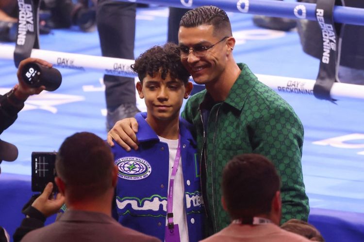 Cristiano Ronaldo berfoto dengan anaknya sebelum pertarungan tinju Day of Reckoning di KIngdom Arena, Riyadh, Arab Saudi, Minggu (24/12/2023) dini hari WIB. (Photo by Fayez NURELDINE / AFP)