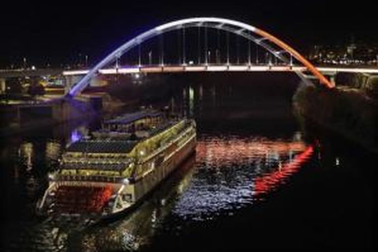 Sebuah kapal hendak lewat di bawah jembatan yang diselimuti dengan warna bendera nasional Perancis, di Nashville, Amerika Serikat, 14 November 2015. Aksi ini merupakan bentuk solidaritas untuk mengenang ratusan orang yang tewas dan terluka dalam aksi serangan teroris yang terjadi di paris pada 13 November malam.