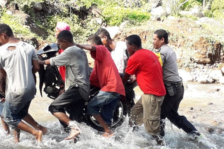 Bripka Bripka Safrul Senja Putra membantu warga menyeberangi di Kali Dagemage, Flores, NTT, Jumat (18/1/2019). 