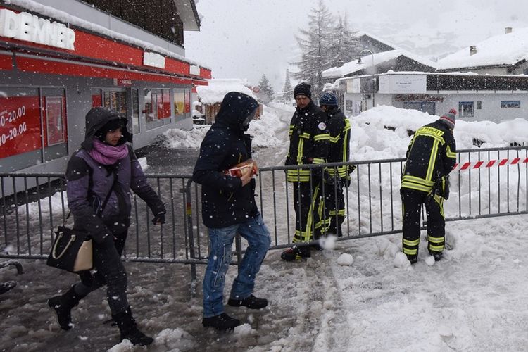 Turis berjalan di tengah salju tebal yang turun di stasiun ski di Zermatt, kawasan pegunungan Alpen di Swiss, Selasa (9/1/2018). Cuaca buruk dan tebalnya salju menutup seluruh akses masuk dan keluar dari kawasan tersebut.