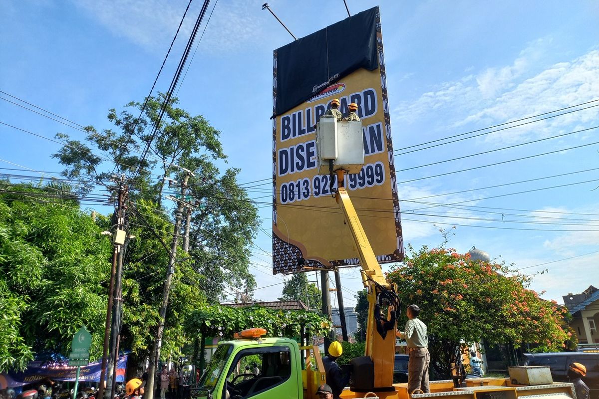 Satpol PP Kota Yogyakarta saat menutup reklame tak berizin, Selasa (13/5/2025)