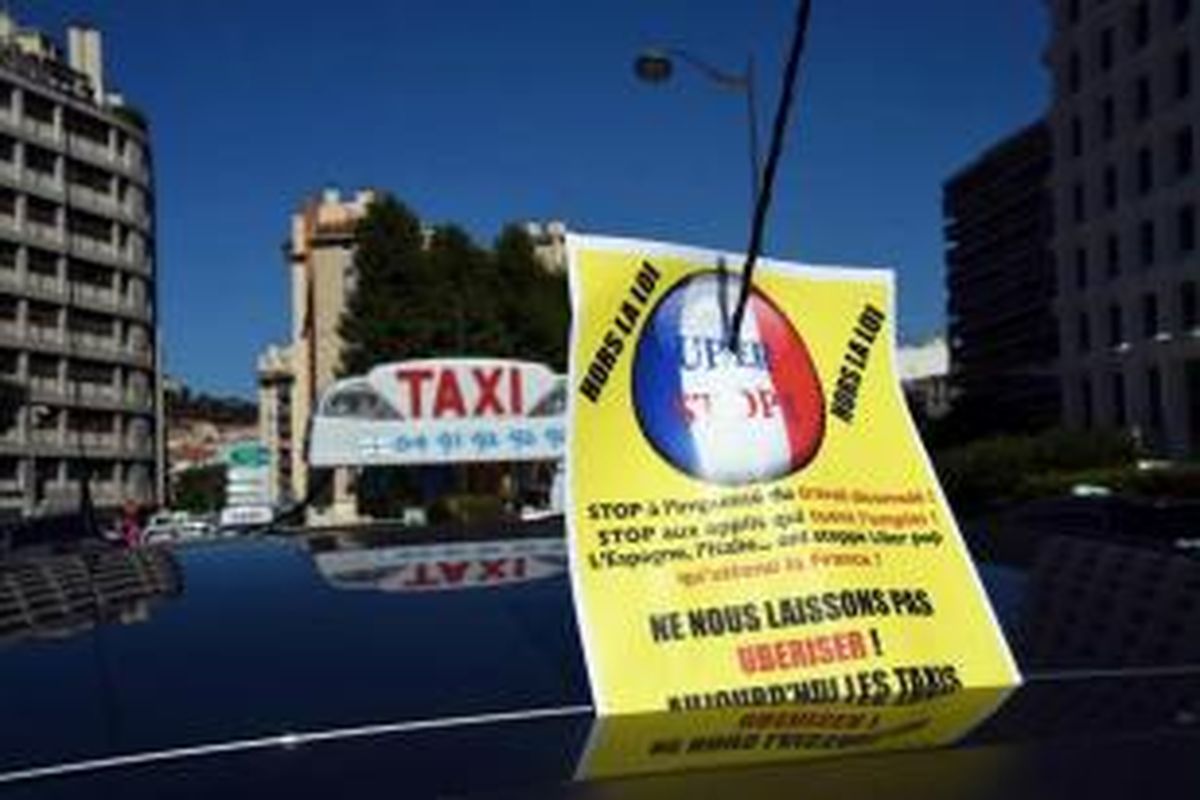Sebuah taksi dengan banner tertulis 'Stop Uber ' terlihat saat demonstrasi para sopir taksi memnentang keberadaan aplikasi layanan sewa mobil Uber di Marseille, 25 Juni 2015.