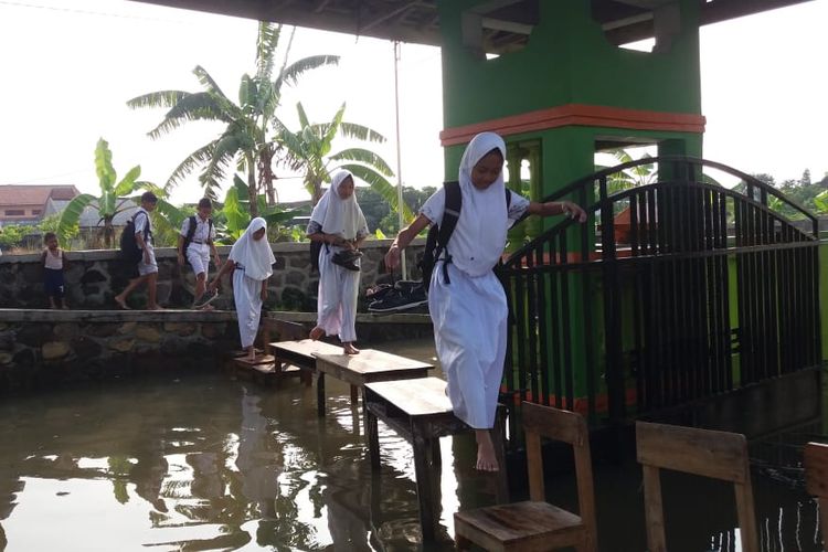 Siswa SDN 1 Sayung saat memasuki lingkungan sekolah yang terendam banjir, Rabu (10/4/209) pagi.