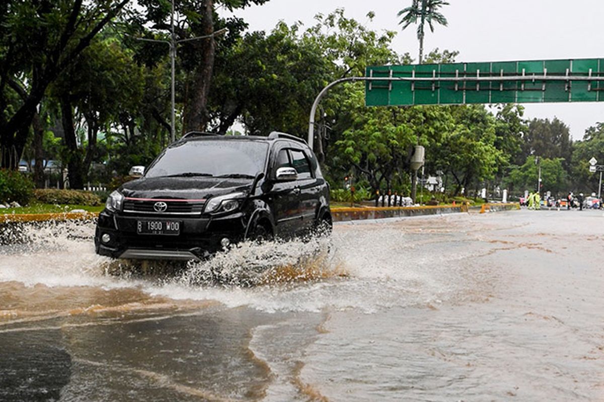 Pengendara mobil melintasi genangan di Jalan Medan Merdeka Barat, Jakarta, Minggu (2/2/2020). Hujan deras yang mengguyur Jakarta pada Minggu (2/2) pagi menyebabkan beberapa ruas jalan di ibu kota tergenang banjir dengan ketinggian 10-50 centimeter.