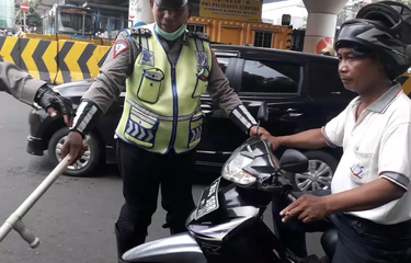 Seorang pengendara motor dihentikan polisi karena kedapatan merokok saat berkendara di kawasan Kampung Melayu, Senin (8/4/2019).