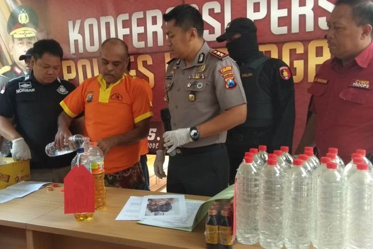 Salah seorang tersangka (Soeharto) saat menunjukkan cara mencampur miras oplosan, dalam rilis pengungkapan kasus di Mapolres Lamongan, Jumat (13/12/2019).