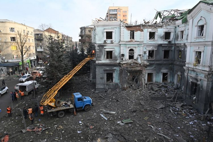Pekerja komunal membersihkan puing-puing yang berserakan di jalan di luar gedung yang rusak di Kharkiv Ukraina pada 24 Januari 2024, satu hari setelah serangan rudal Rusia di seluruh negeri.