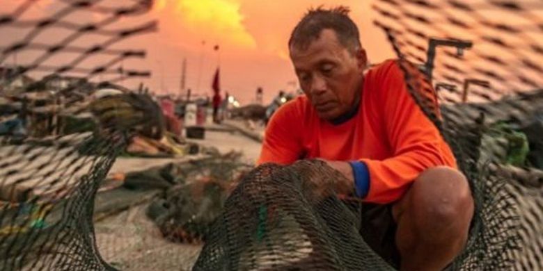 Seorang nelayan memperbaiki jaring di kawasan dermaga Kampung Bahari Tambaklorok, Semarang, Jawa Tengah, Senin (18/11/2019). 