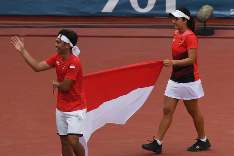 Ganda campuran Indonesia Aldila Sutjiadi (kanan) dan Christopher Rungkat membawa bendera Merah Putih seusai menang atas petenis Thailand Luksika Kumkhum dan Sonchat Ratiwatana pada final tenis ganda campuran Asian Games 2018 di Jakabaring Sport City, Palembang, Sumatera Selatan, Sabtu (25/8/2018).