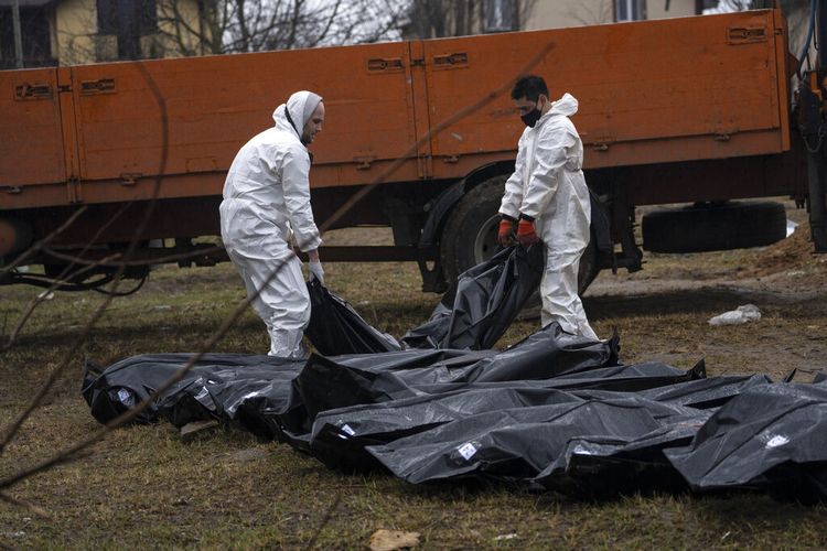 Pekerja pemakaman membawa mayat seorang pria dari kuburan massal untuk diidentifikasi di kamar mayat, di Bucha, di pinggiran Kyiv, Ukraina, Minggu, 10 April 2022.