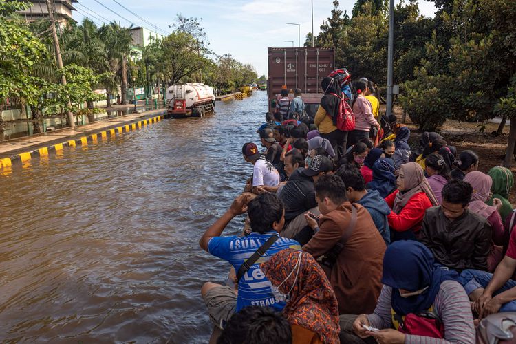 Sejumlah karyawan kawasan industri pelabuhan menumpang truk trailer untuk menerobos banjir limpasan air laut ke daratan atau rob di kawasan Pelabuhan Tanjung Emas Semarang, Jawa Tengah, Jumat (27/5/2022). Karyawan sejumlah pabrik setempat mulai membersihkan sisa-sisa banjir rob di dalam pabrik yang sudah berangsur surut, meskipun air rob masih merendam sejumlah titik akses keluar - masuk kawasan industri pelabuhan dengan ketinggian bervariasi hingga sekitar 70 sentimeter.