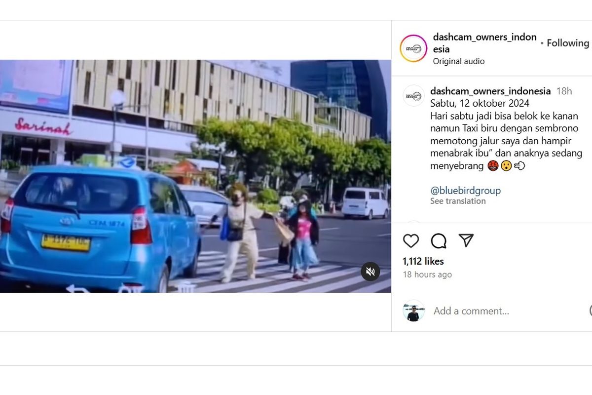 Sebuah taksi Blue Bird terlihat memotong lajur mobil yang berada di dekatnya dan nyaris menabrak pejalan kaki di zebra cross.