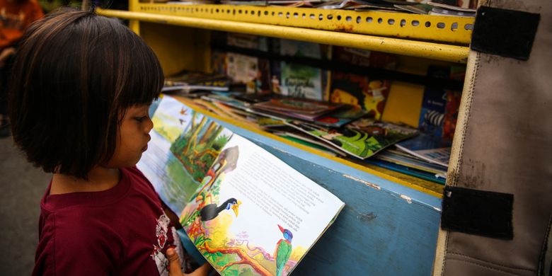 Anak-anak membaca buku di bemo perpustakaan di Jalan Karet Pasar Baru Barat II, Tanah Abang, Jalarta Pusat, Jumat (7/12/2018). Pak Sutino (58) adalah sopir bemo yang merintis bemo tuanya menjadi perpustakaan keliling bagi anak-anak sejak tahun 2013.  Pak Sutino (58) adalah sopir bemo yang merintis bemo tuanya menjadi perpustakaan keliling bagi anak-anak sejak tahun 2013.